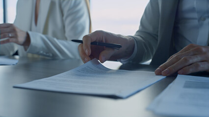 Closeup hands checking agreement in office. Business partners reading contract