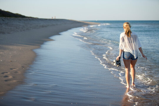 Young Woman Carrying Camera while Walking along Beach, Palm Beach Gardens, Palm Beach, Florida, USA
