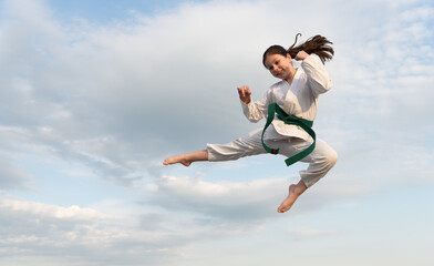 martial art concept. teen girl practicing martial art. girl martial fighter jump on sky background