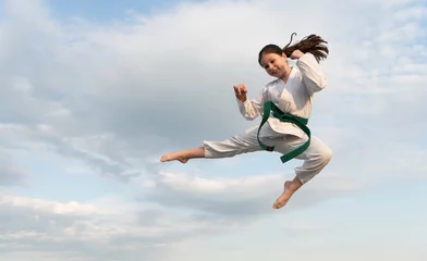 Fotobehang martial art concept. teen girl practicing martial art. girl martial fighter jump on sky background © be free