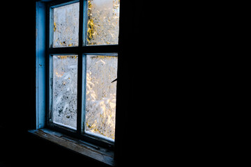 Wooden window in an old house. Frost patterns on the window glass. Snowy spruce. Unexpected angle. Copy space.