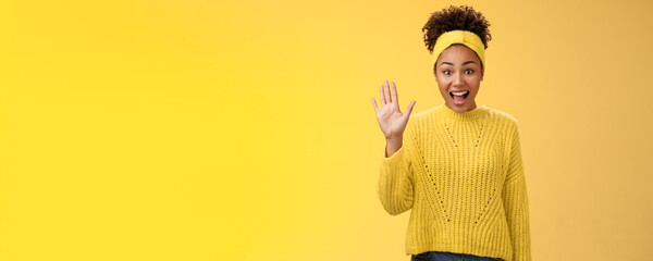 Friendly outgoing excited cute millennial female coworker newbie greeting team waving palm hi hello gesture energized get know new people welcoming greeting friends, standing yellow background - obrazy, fototapety, plakaty