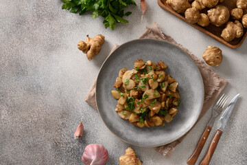 Roasted Jerusalem artichoke root, sunchokes on dark brown. View from above. Copy space.