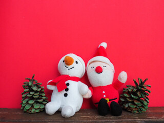 Plush sewn Christmas soft toys on a red background. Painted cones. A little smiling snowman and a funny Santa Claus. New Year's Eve and Christmas. Copy space. Cute kind children's toys.