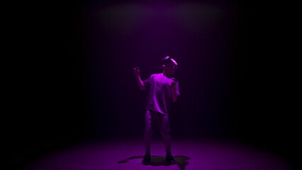 Neon man experiencing virtual reality in dark cyberspace. Focused player explore