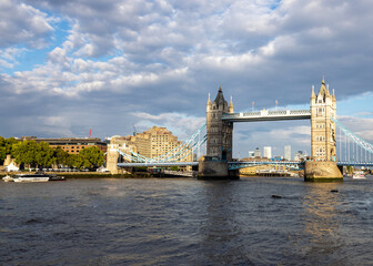 Fototapeta na wymiar Famous London bridge over the river Thames the Tower Bridge in broad daylight, sunlit under the cloudy sky, side view.