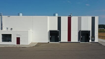 Fototapeta na wymiar Belarus - 29.08.2022: Loading and unloading area for trucks at the rear of the production building with roller shutters. Entrance for trucks at a medical plant.