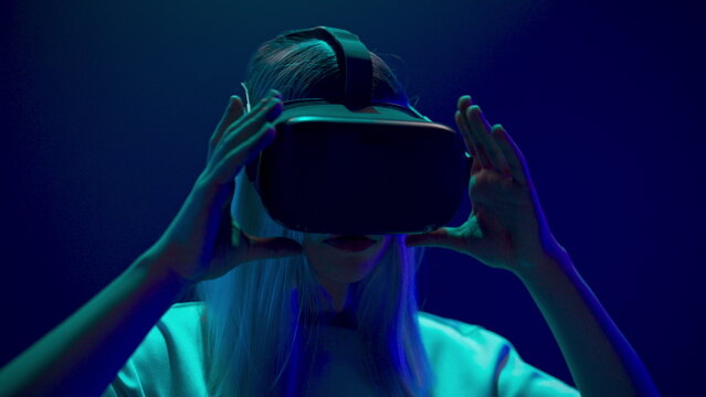 Shocked gamer raising headset room. Woman taking off virtual reality glasses