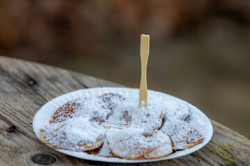 Selective focus of poffertjes on wooden table, Traditional Dutch batter treat with white icing sugar on top, Resembling small fluffy pancakes they are made with yeast and buckwheat flour, Netherlands.