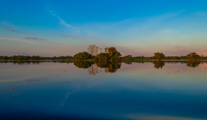 Mirror reflections on the water of Rio Amazonas in Brazil at sunset during a canoe excursion in the middle of the rain forest