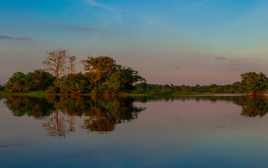 Mirror reflections on the water of Rio Amazonas in Brazil at sunset during a canoe excursion in the middle of the rain forest