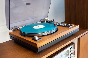 Vintage Stereo Turntable Vinyl Record Player with Open Plastic Lid and Wooden Plinth Standing Above Amplifier. Home Retro Audio Sound Equipment.