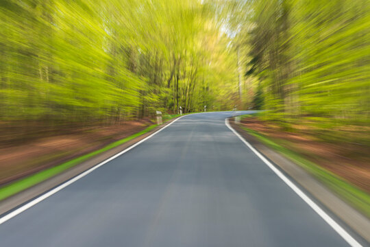 Driving along paved road through the spring forest at Amorbach in Odenwald, in Lower Franconia, Bavaria, Germany