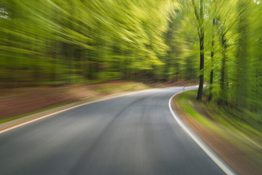 Driving along paved road through the spring forest at Amorbach in Odenwald, in Lower Franconia, Bavaria, Germany