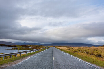 Country road through moor landscape with dense cloudy sky at Rannoch Moor in Scotland, United Kingdom