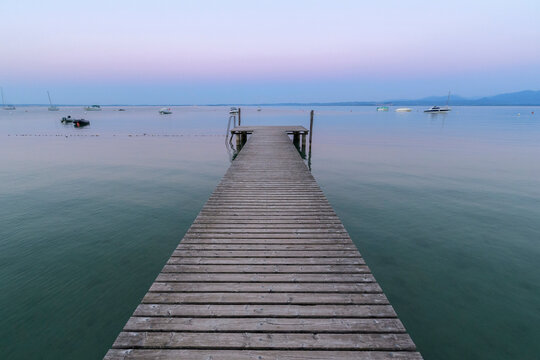 Wooden jetty on Lake Gardo (Lago di Garda) at dawn in Bardolino in Veneto, Italy