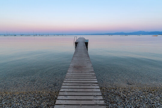 Wooden jetty on Lake Gardo (Lago di Garda) at dawn in Bardolino in Veneto, Italy