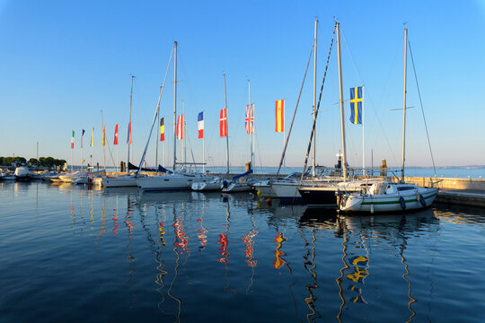 Row of boats and colorful European flags in the harbor marina on Lake Garda (Lago di Garda) at Bardolino in Veneto, Italy