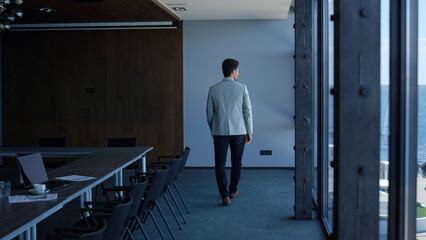 Executive man walking alone in modern company office. Ceo thinking or waiting
