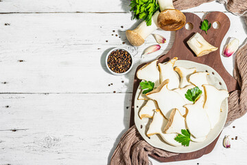 Fresh Pleurotus eryngii mushrooms on wooden background. Raw king oyster eringi with spices and herbs
