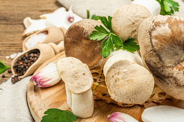 Fresh Pleurotus eryngii mushrooms on wooden background. Raw king oyster eringi with spices and herbs