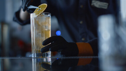 Bartender hands forceps putting lemon slice in glass closeup. Cocktail concept