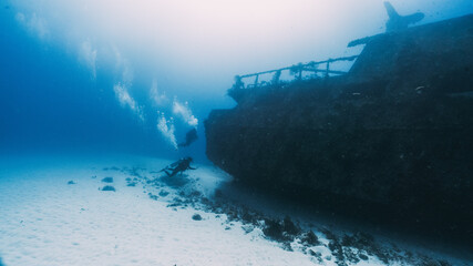 two scuba diver swimming into a deep wreck
