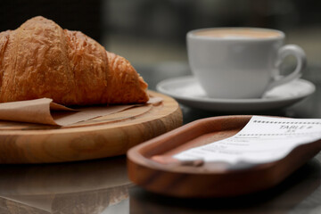 Tips and receipt near croissant on table, closeup