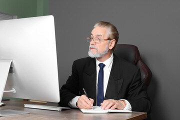 Senior boss working at wooden table in modern office