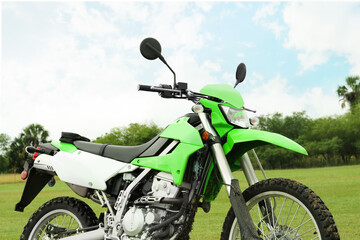 Naklejka premium Green stylish cross motorcycle on grass outdoors