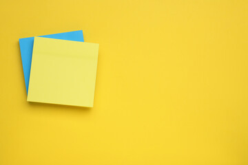 Paper notes on yellow background, top view. Space for text