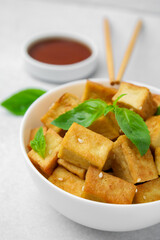 Delicious fried tofu, basil and sesame seeds served on light grey table, closeup