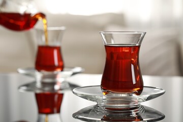 Glass of traditional Turkish tea on table indoors, space for text