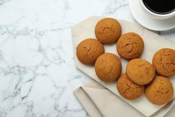 Tasty oatmeal cookies and cup of coffee on white marble table, flat lay. Space for text