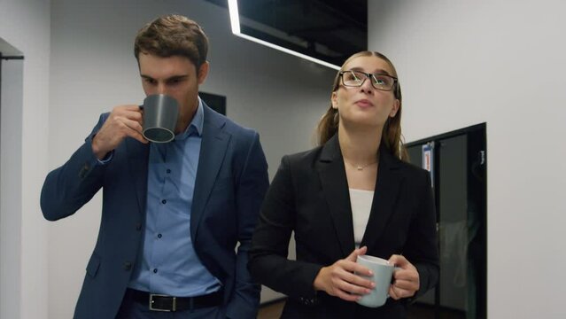 Workers walking office hallway on lunch break. Friendly company employees talk