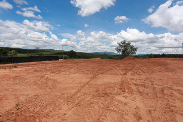 Empty dry cracked swamp reclamation soil, land plot for housing construction project with car tire print in rural area and beautiful blue sky with fresh air Land for sales landscape concept