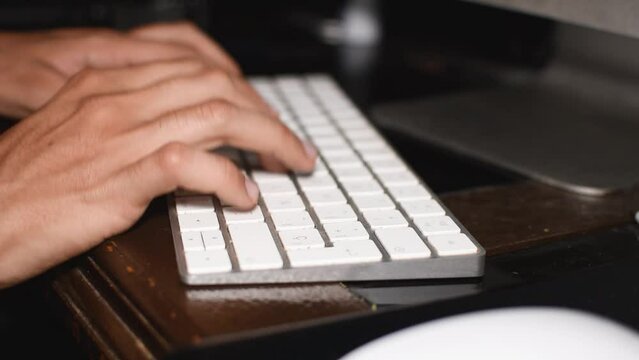 Manos de un hombre joven delgado typeando o tecleando en un teclado de computadora investigando o escribendo en el teclado 