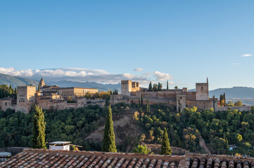 Aerial view of the Alhambra Palace in Granada, Spain with snow-capped Sierra Nevada mountains in the background.