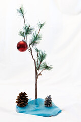 Small Christmas tree with one red ornament on a white background as in A Charlie Brown Christmas