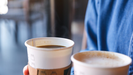 Closeup of a woman holding and serving two cup of hot coffee in cafe