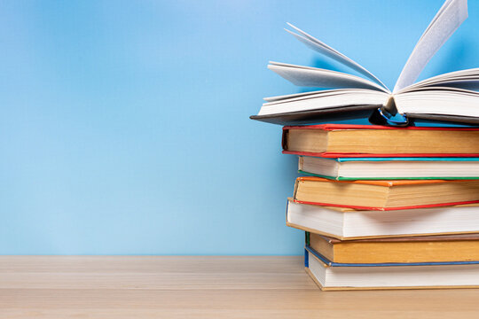 Composition with vintage old hardback books, diary and open book whith old pages on wooden table and blue background. Books stacking. Back to school. Copy Space. Education background. - Powered by Adobe