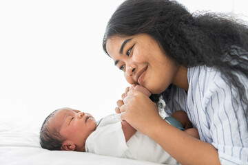 Happy African American mother and newborn baby on bed. Young mom or nurse taking care newborn in...