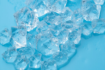 Ice cubes and ice shards with water drops on a blue background. The concept of cold and freshness