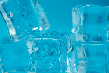 Ice cubes and ice shards with water drops on a blue background. The concept of cold and freshness