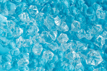 Ice cubes and ice shards with water drops on a blue background. The concept of cold and freshness