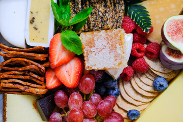 Close up top down view of assortment of fruits cheeses crackers in a box. Concept for food delivery catering or gift for holiday season or packaging mock up. Selective focus