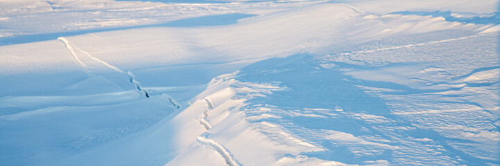 Crack in the ice cover. Snow covered ice. Cracked ice floes on the sea in the Arctic. Polar region. Wide panoramic texture for background and design.