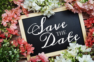 Save the Date typography text written on wooden blackboard with flower bouquet decorate on wooden background