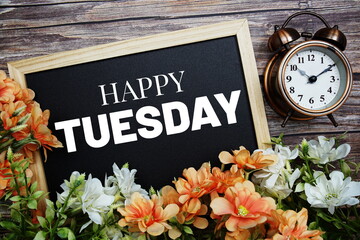 Happy Tuesday typography text written on wooden blackboard with flower bouquet decorate on wooden background