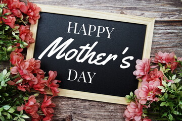 Obraz na płótnie Canvas Happy Mothers Day typography text written on wooden blackboard with flower bouquet decorate on wooden background